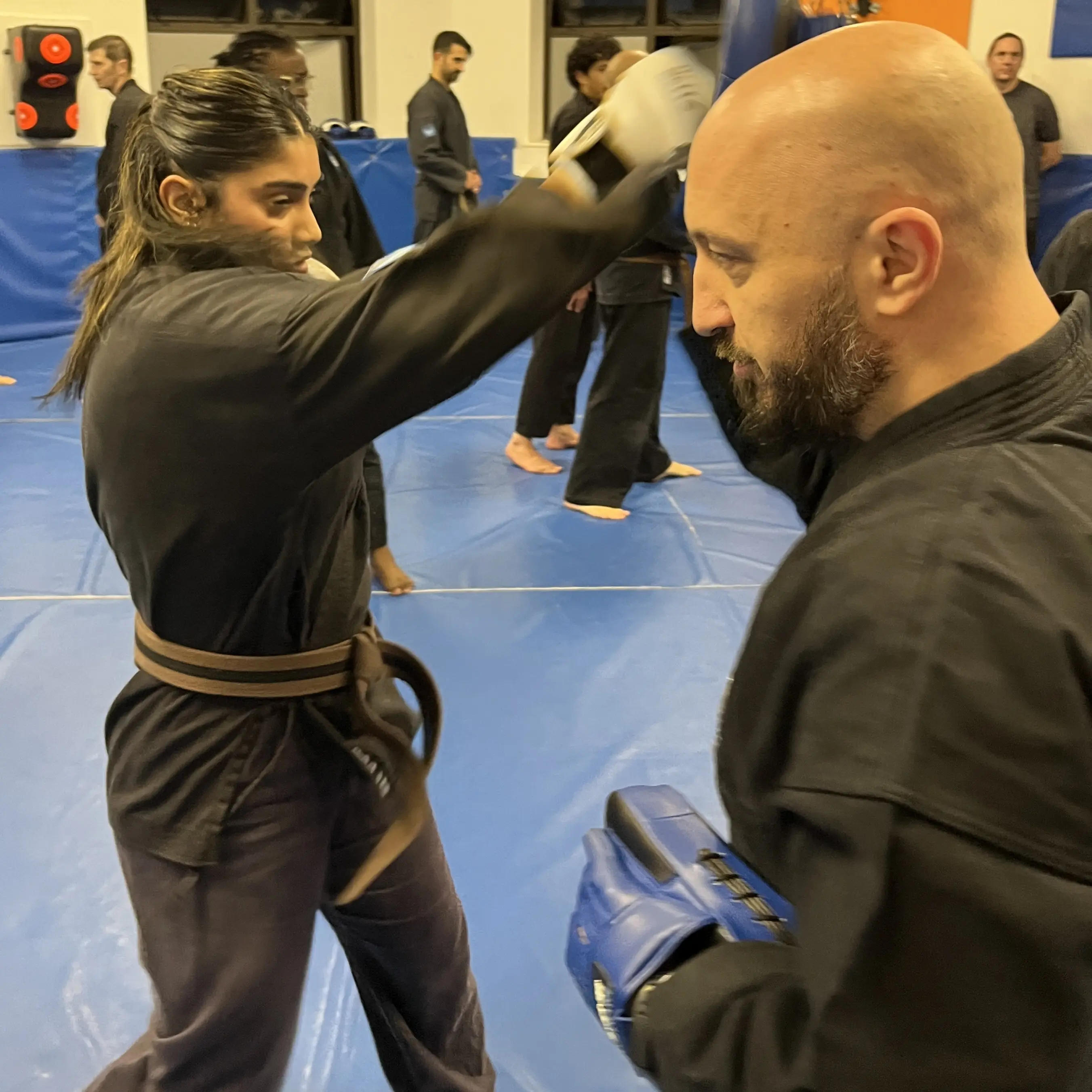 Olgun Tiltay of  Shuhari Self Defence doing pad work with a student in a martial arts class in Slough
